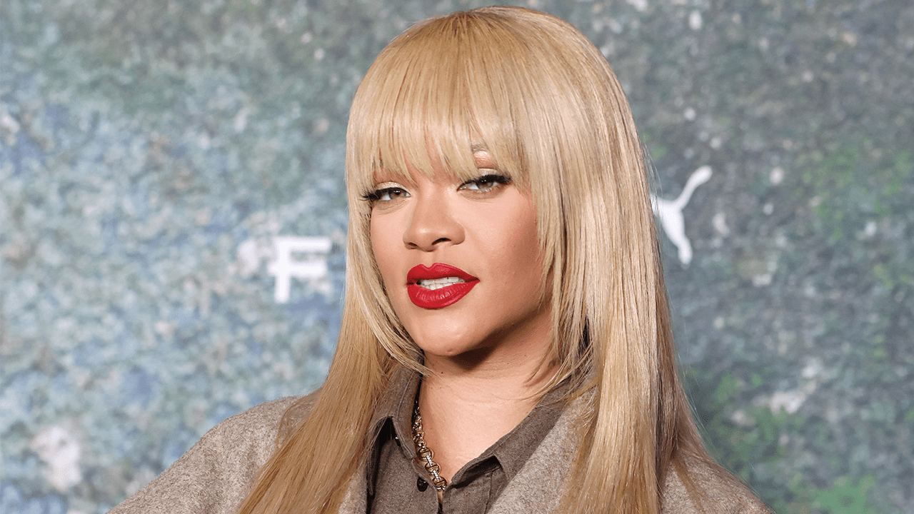 Rihanna at a Fenty event with long blonde hair and blunt bangs.